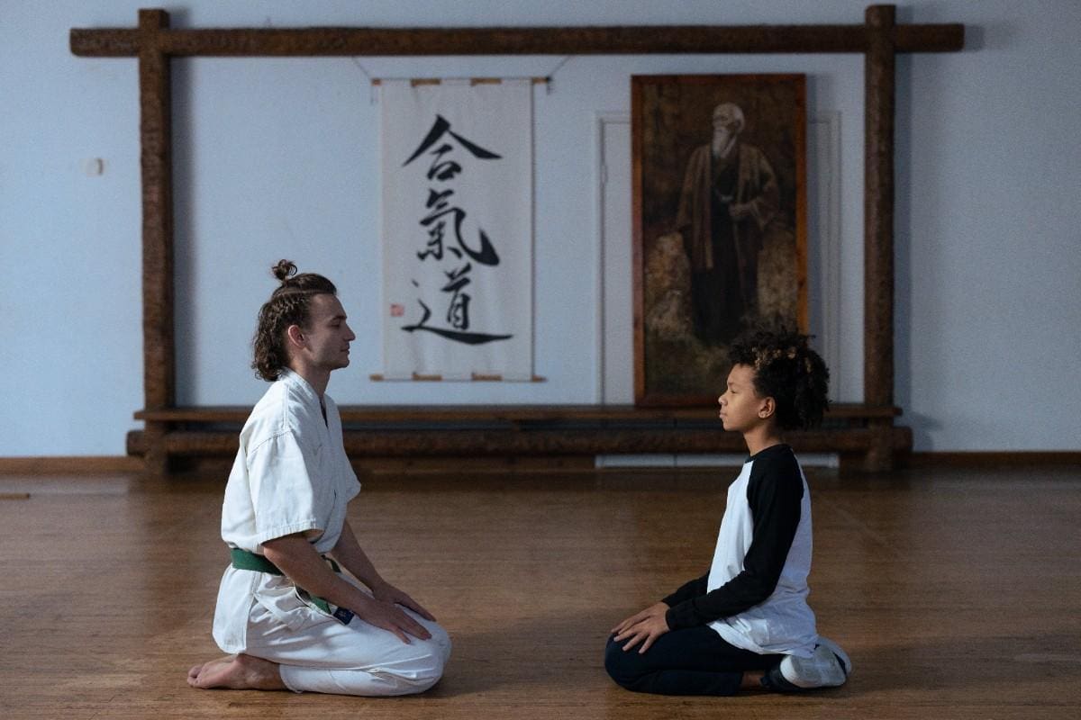 Instructor meditating with a student in a martial arts class